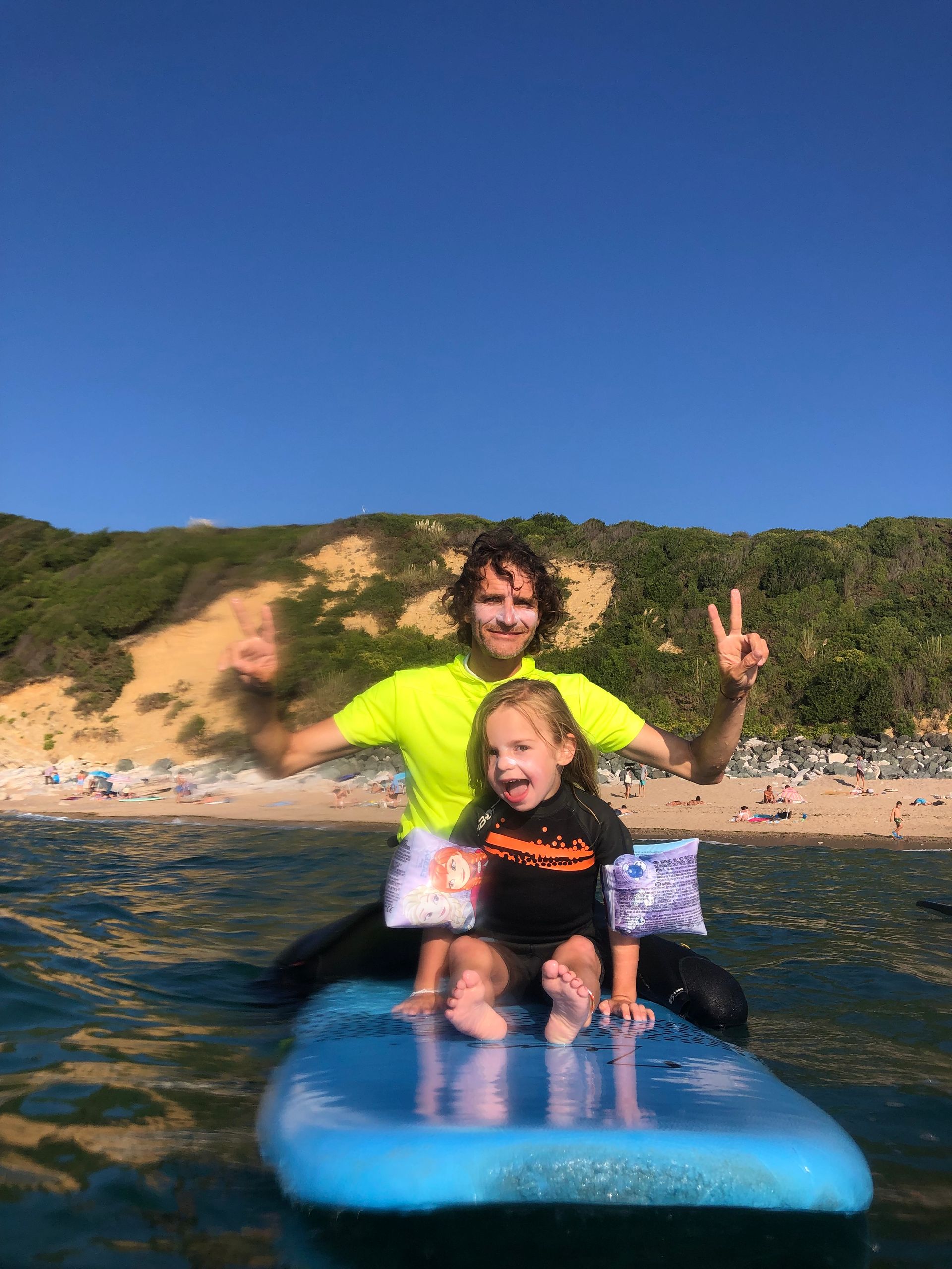Jeune enfant avec un adulte assis sur une planche de surf dans l'eau