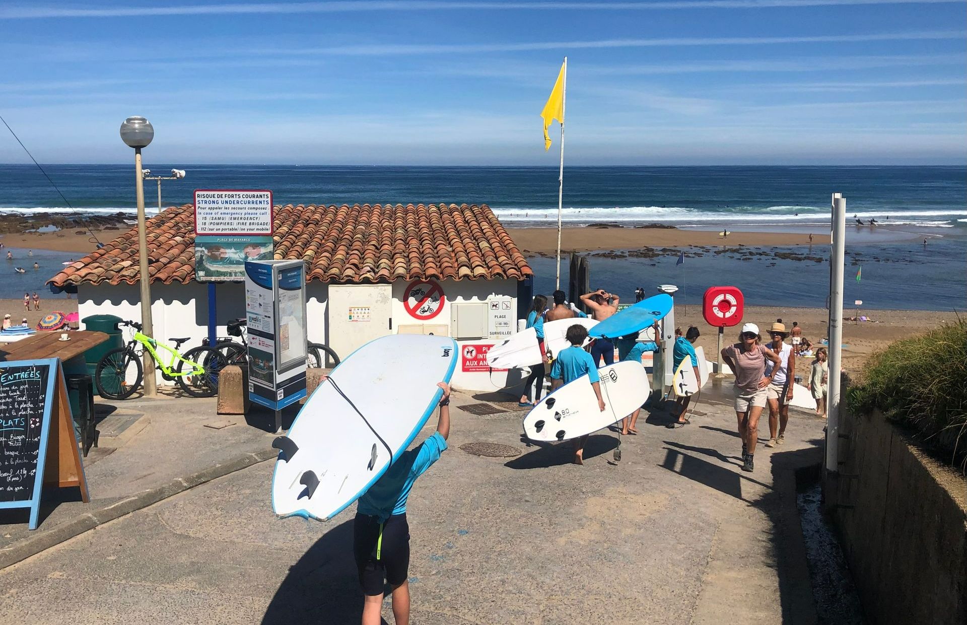 Groupe d'élèves au bors de la plage avec leur planche pour prendre leur cours de surf