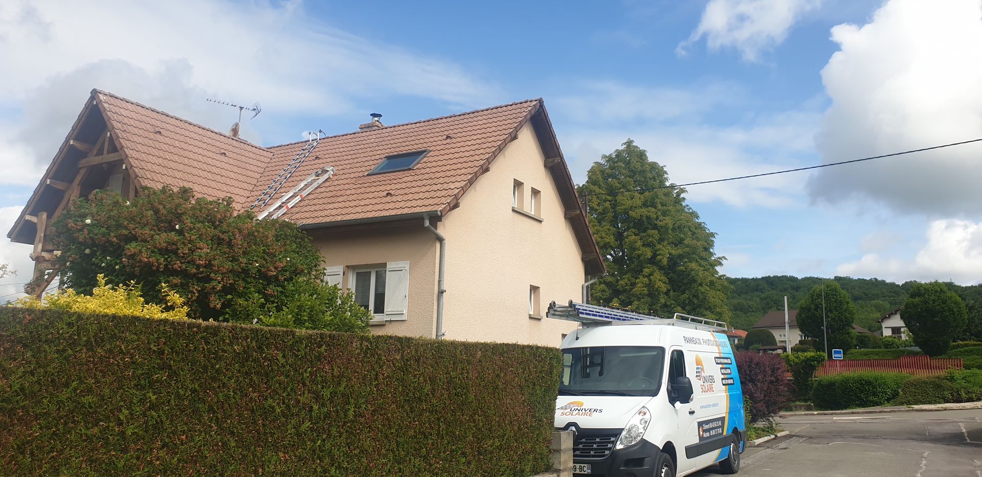 Photo d'une maison avec des échelles allant sur le toit et un camion de l'entreprise devant