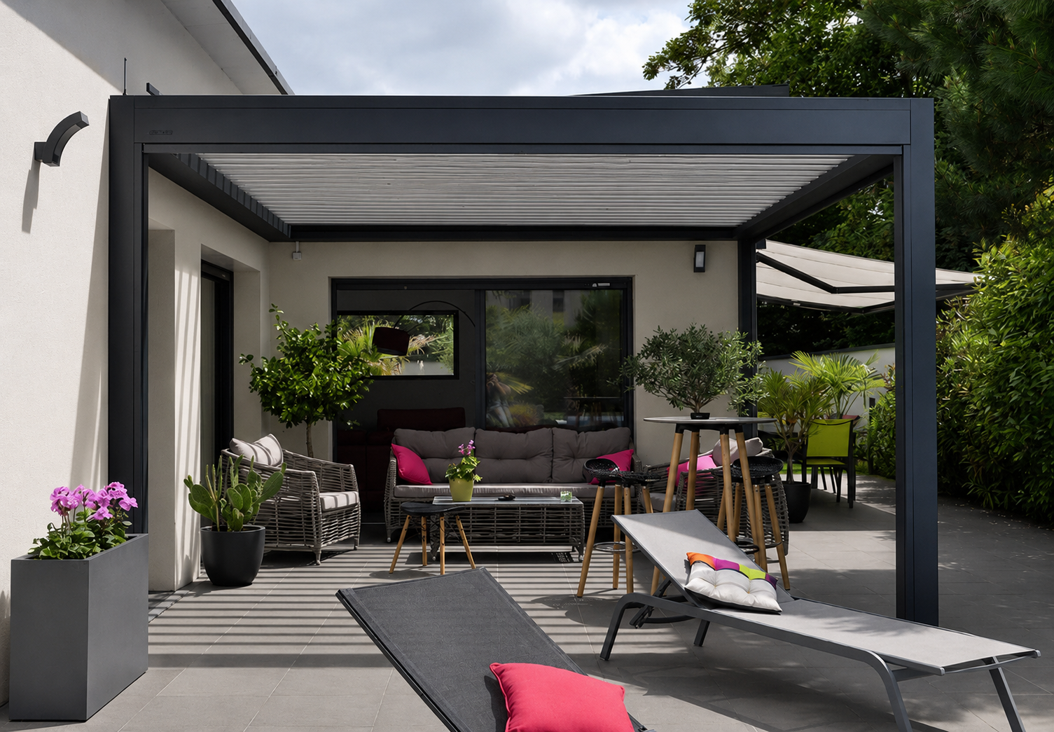 Pergola surplombant un patio avec des sièges, reliée à un bâtiment doté de portes vitrées et offrant une vue panoramique.