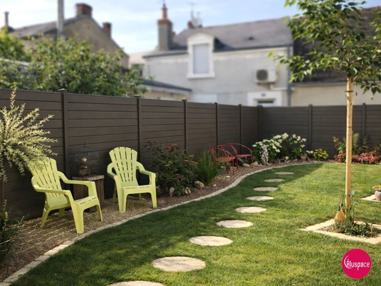 Pelouse verte avec parterres de fleurs, chaises vert citron et clôture marron dans un jardin.