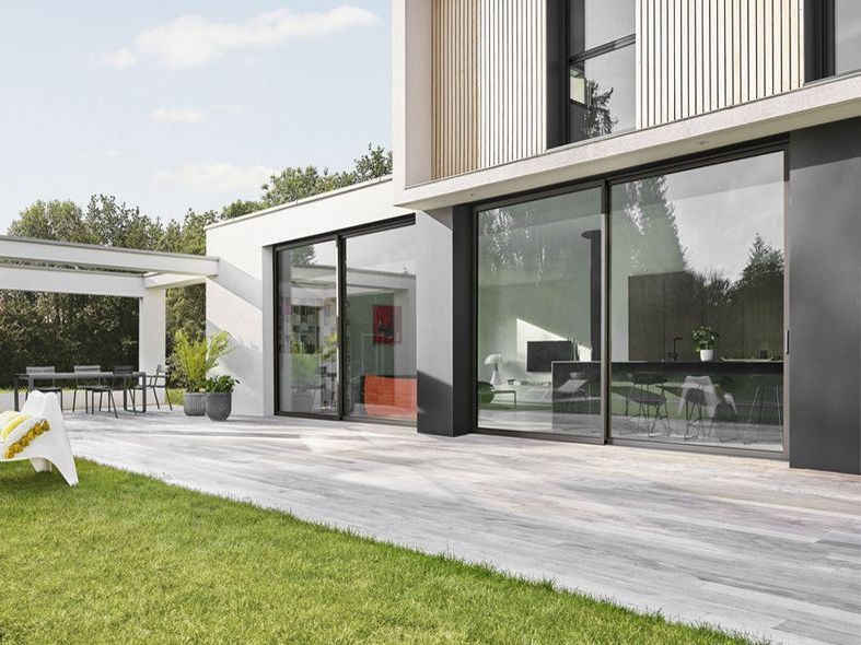 Maison moderne avec baie vitrée entourée d'une terrasse avec carrelage