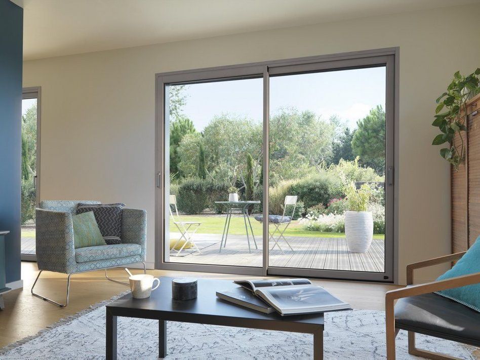 Salon avec baie vitrée donnant sur une terrasse et un jardin arboré