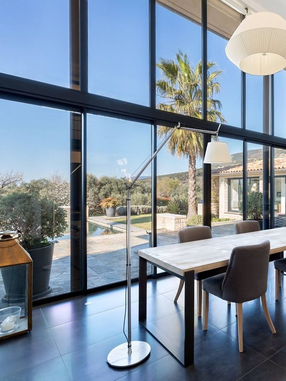 Villa avec une immense baie vitrée donnant sur une terrasse et une piscine