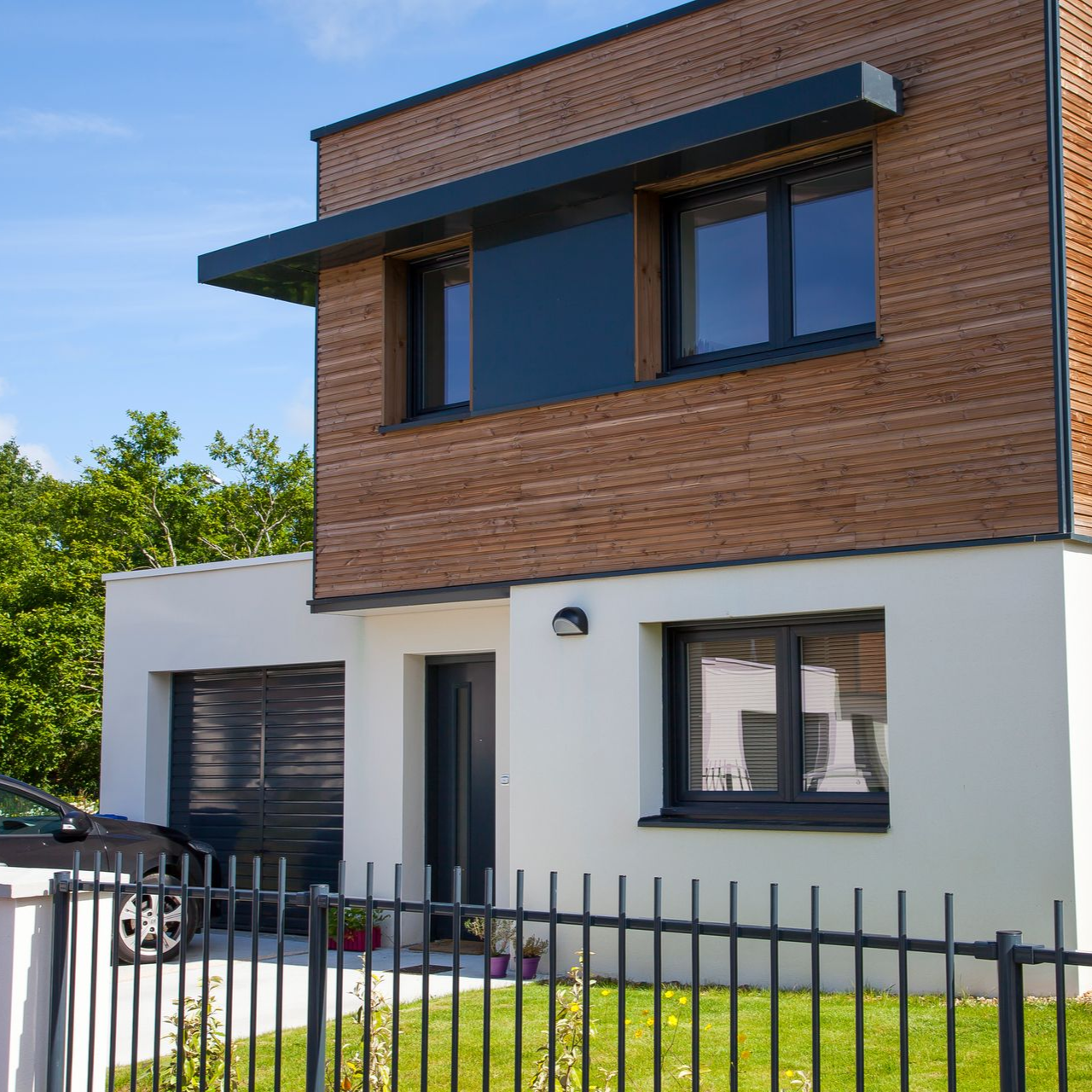 Maison moderne avec bardage en bois, menuiseries en aluminium anthracite et clôture