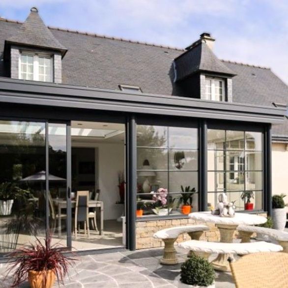 Véranda installée devant une maison avec un toit en ardoise