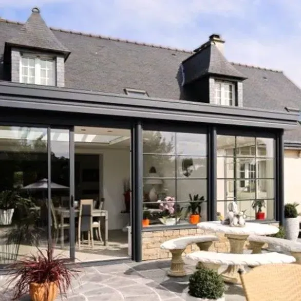 Véranda installée devant une maison avec un toit en ardoise