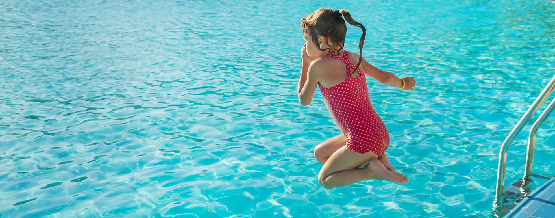 Une petite fille plongeant dans une piscine.