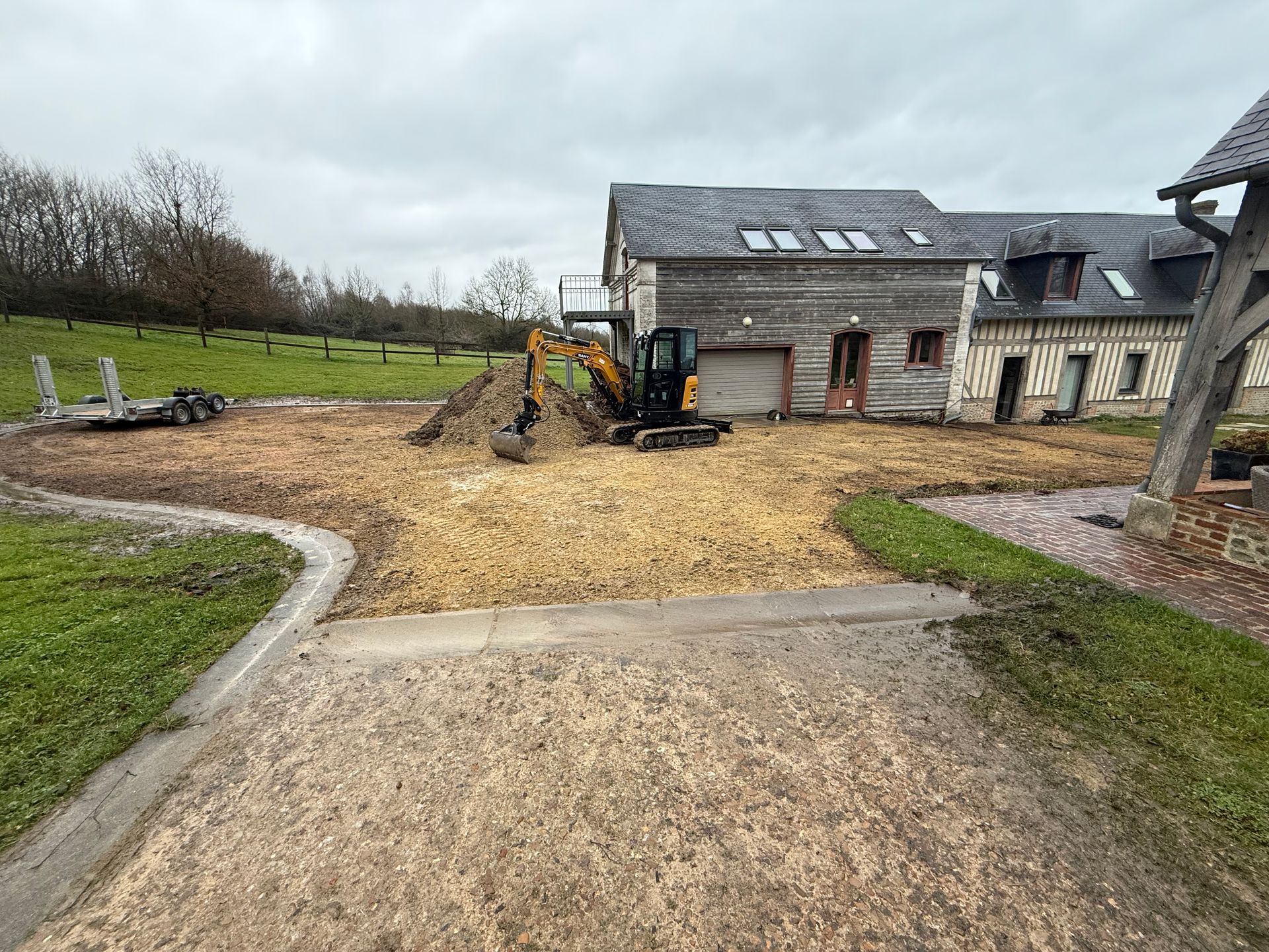 Pelleteuse sur de la terre près d'un bâtiment rustique ; chantier de construction.