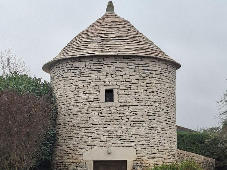 Une tour en pierre au toit conique et percée d'une petite fenêtre centrale.