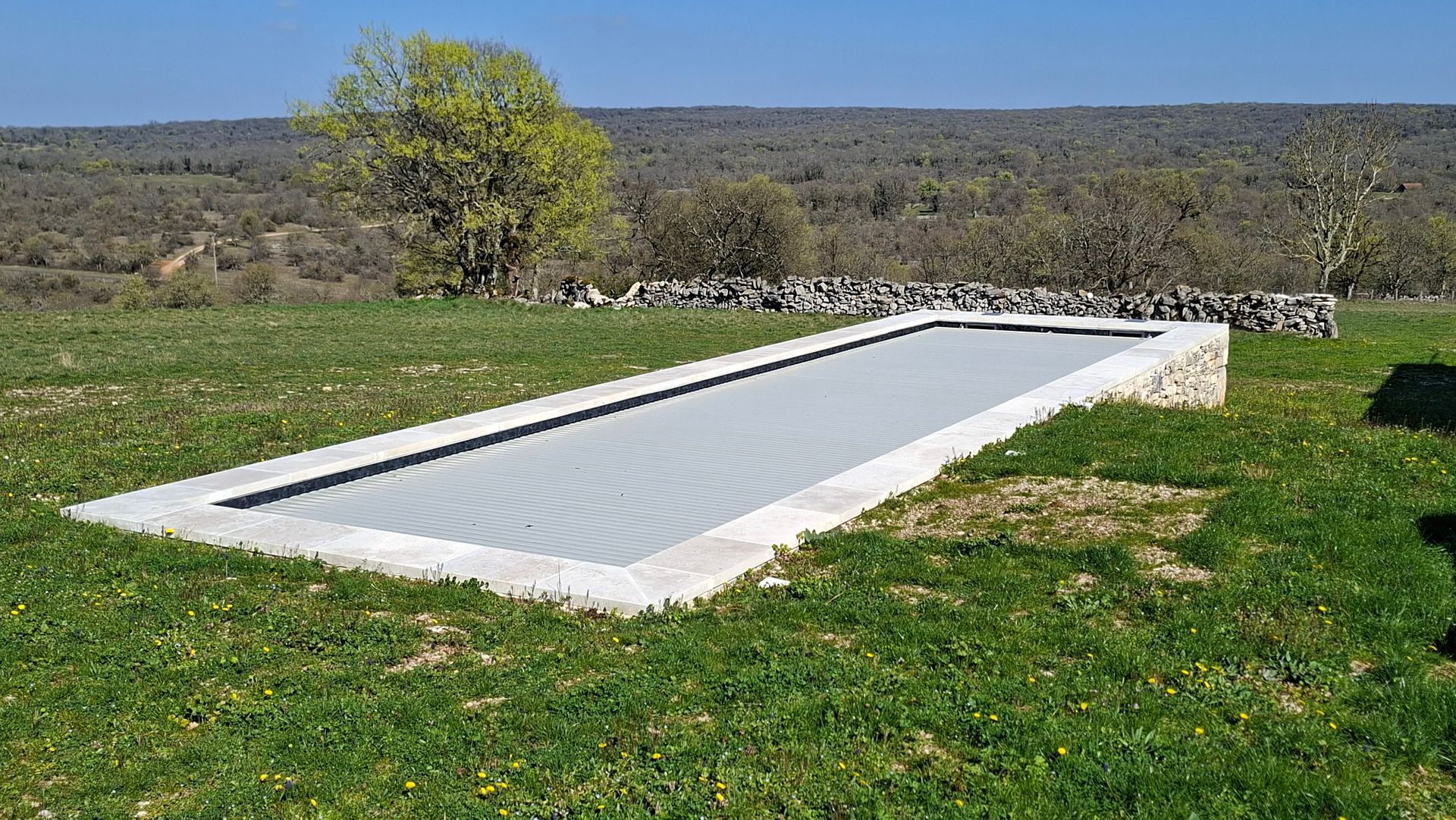 Une piscine rectangulaire avec une couverture de sécurité grise.