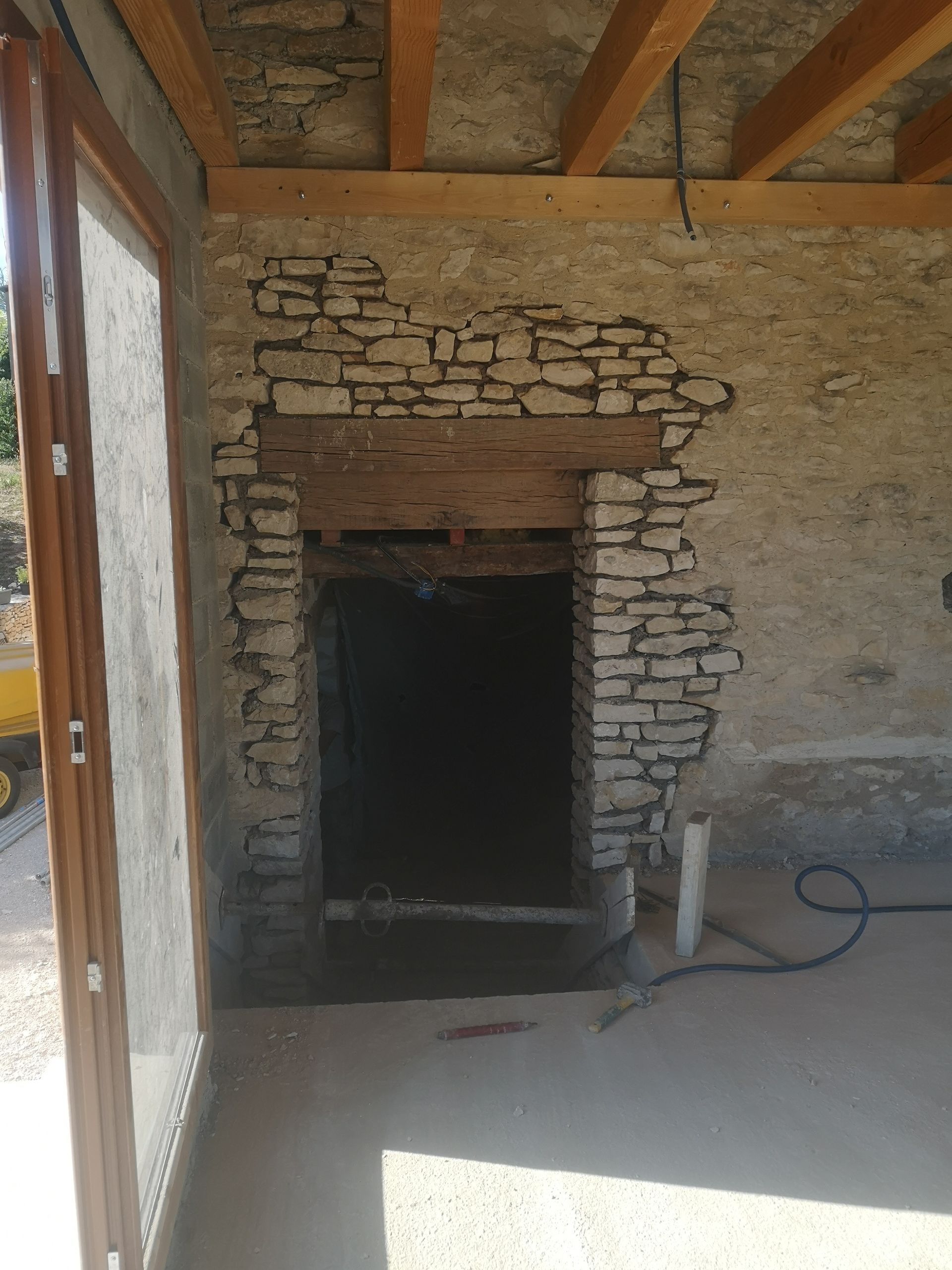 Une porte cintrée en pierre, surmontée d'un linteau en bois.