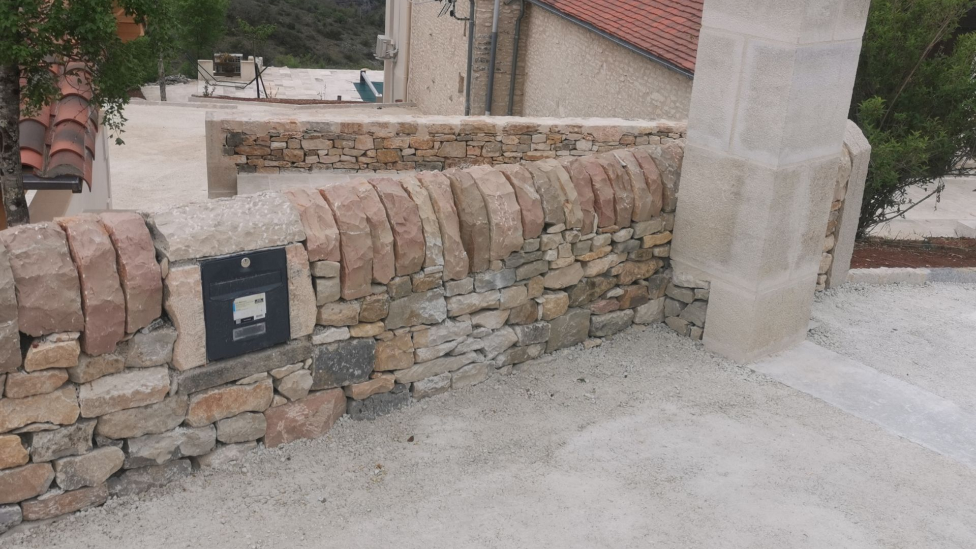 Un mur de pierres anciennes avec une colonne en béton.