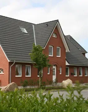 Ein großes rotes Backsteinhaus mit einem schwarzen Dach