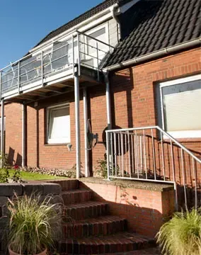 Ein Backsteinhaus mit einem Balkon und einer Treppe, die dorthin führt