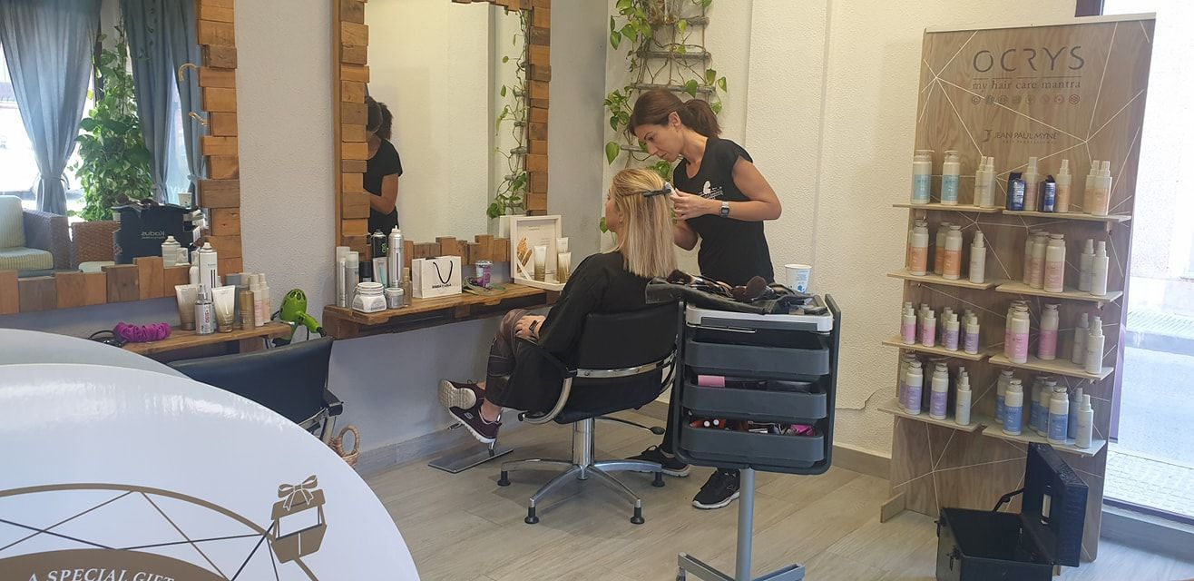 Una persona se peina en una peluquería. La estilista sostiene un cepillo mientras peina a su clienta.