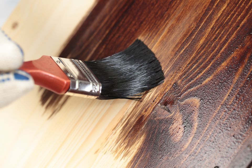 Eine Person bemalt ein Stück Holz mit einem Pinsel