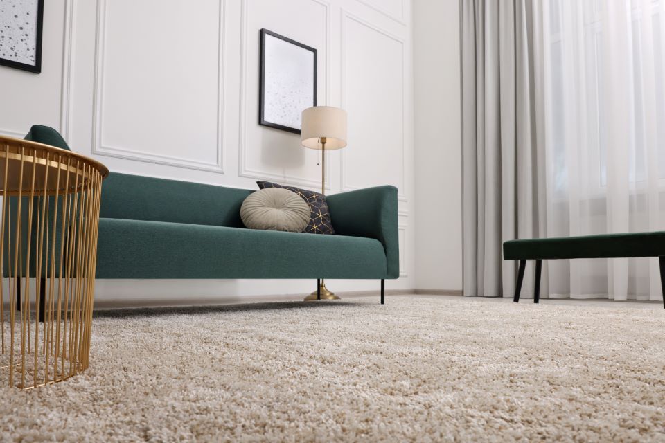 Ein Wohnzimmer mit einer grünen Couch und einem weißen Teppich.
