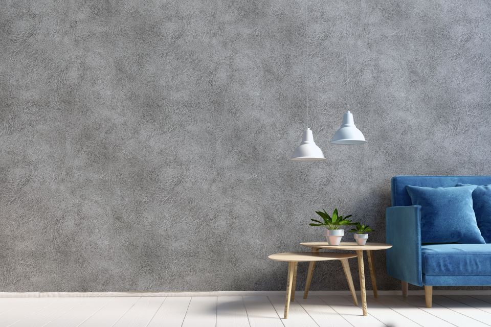 Ein Wohnzimmer mit einem blauen Sofa, zwei Tischen und einer Betonwand.