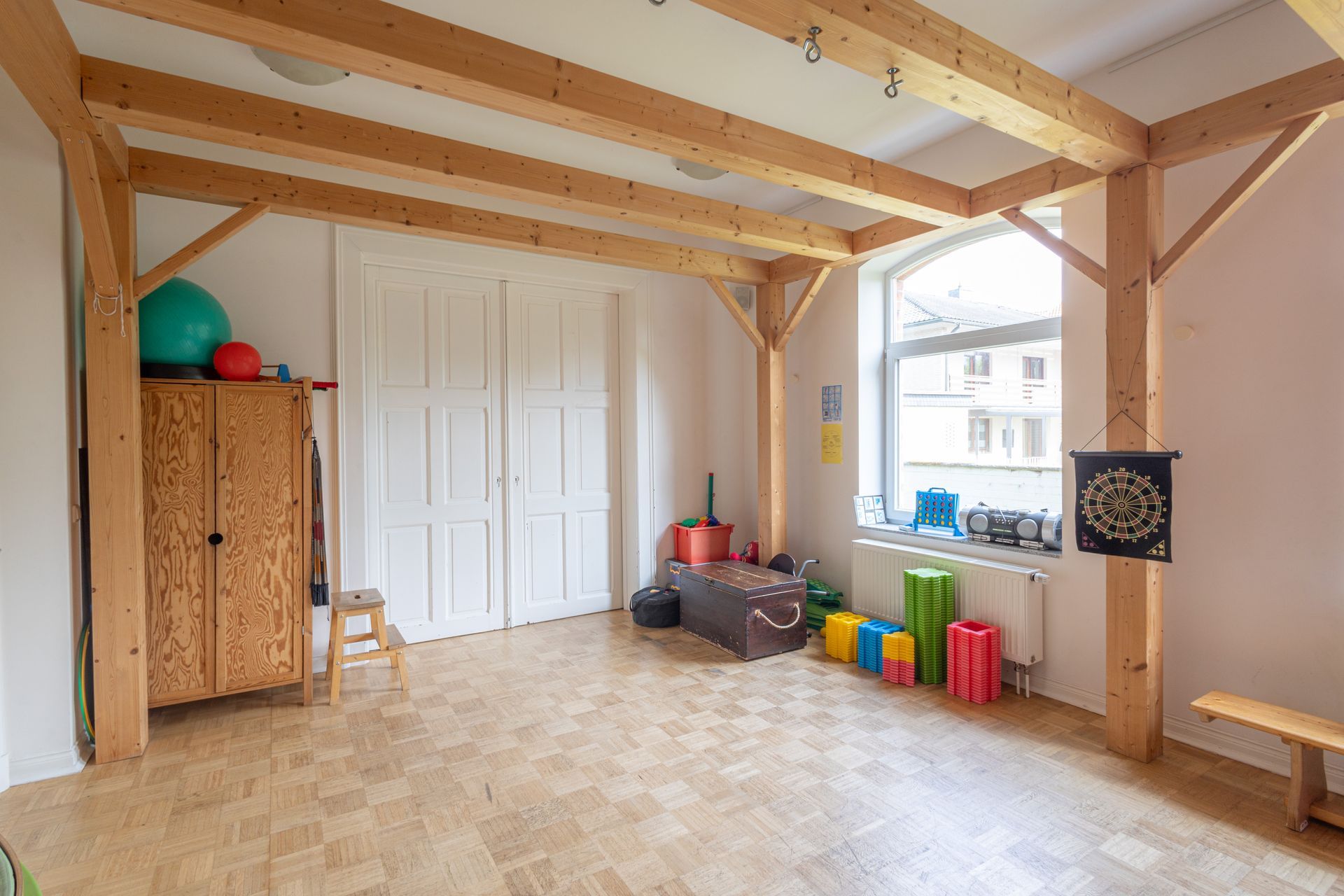 Ein großer aufgeräumter Raum mit Holzbalken und Holzboden.