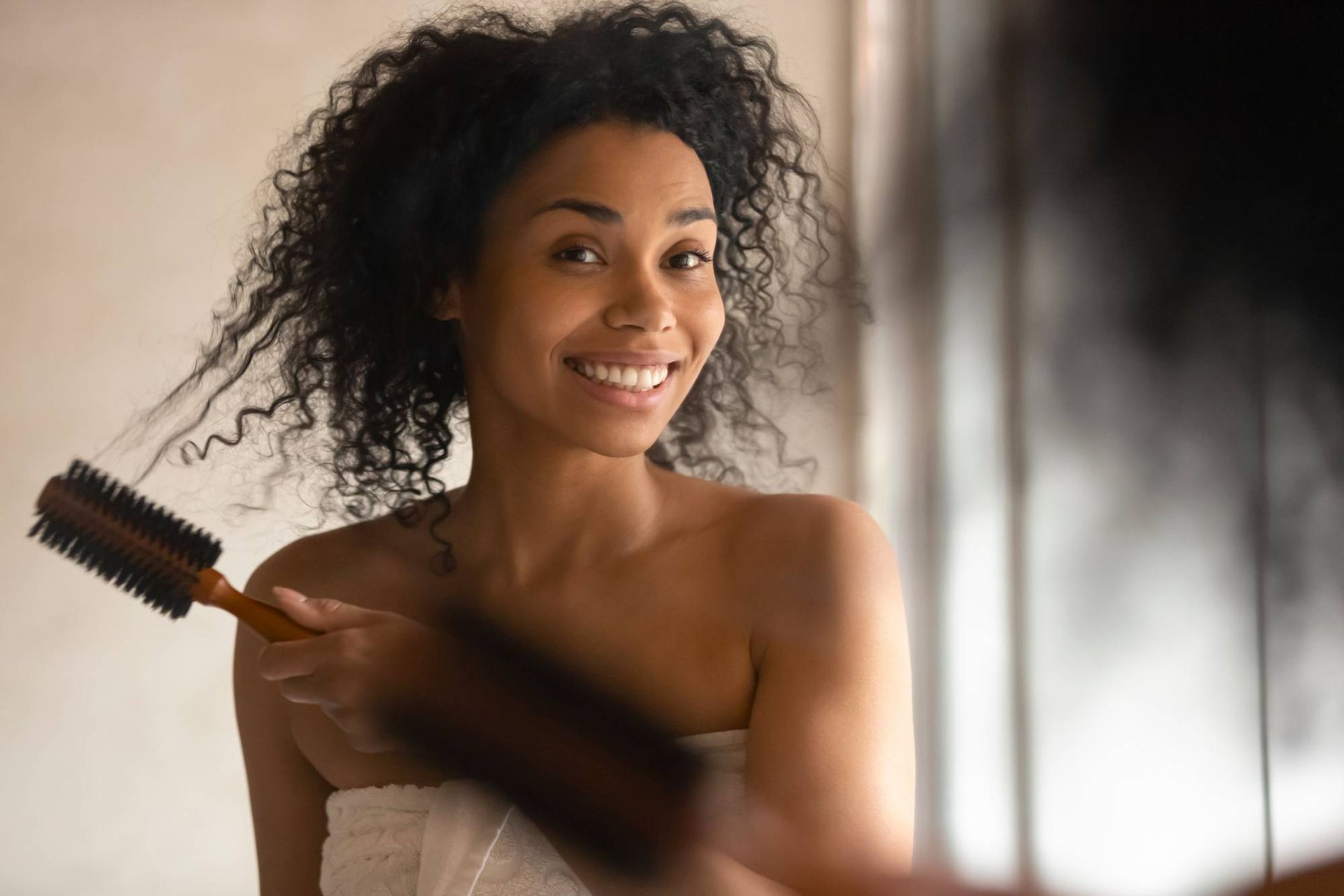 Una donna si spazzola i capelli davanti allo specchio.