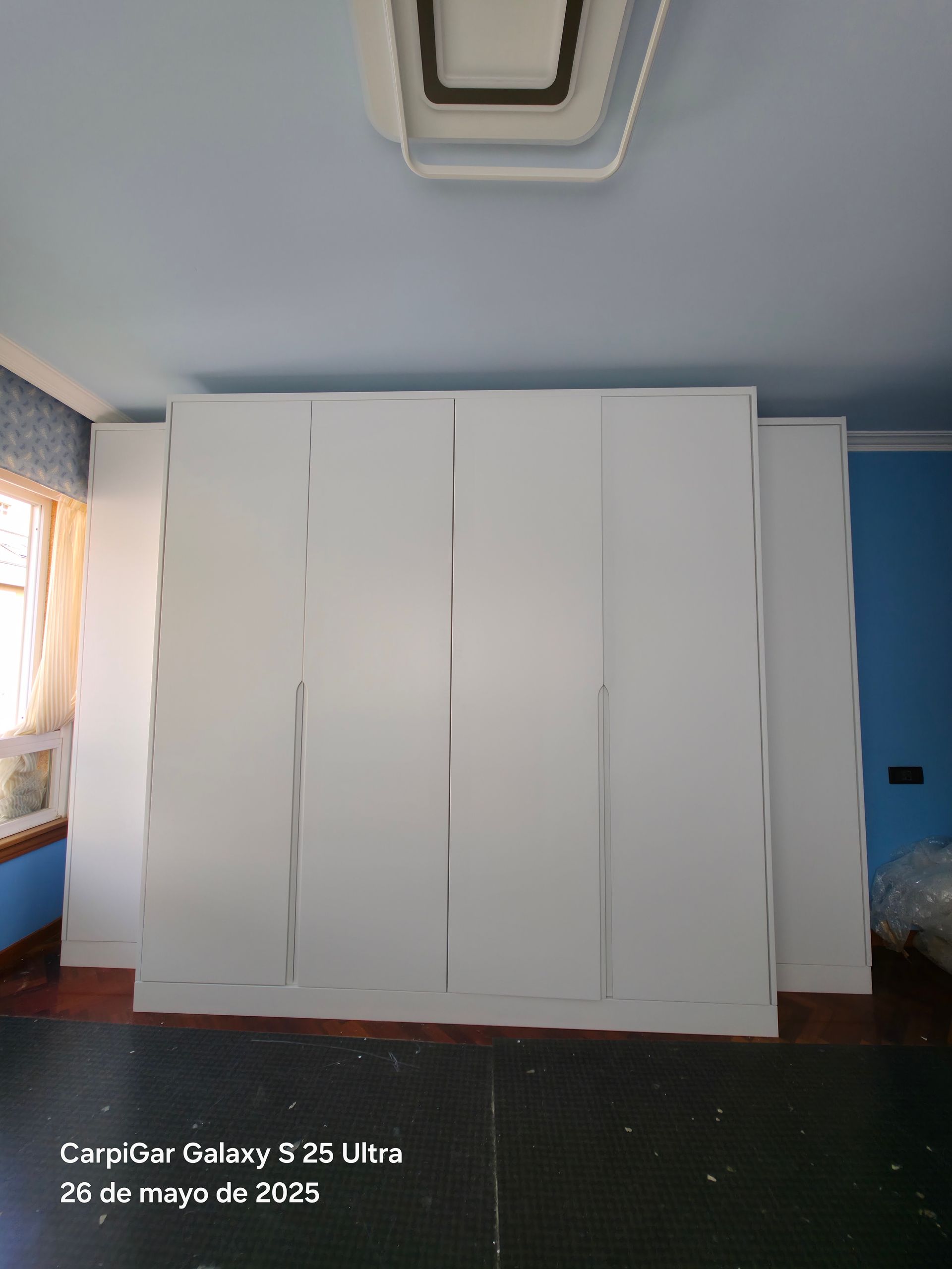 Una habitación con muchos armarios blancos y un techo azul.