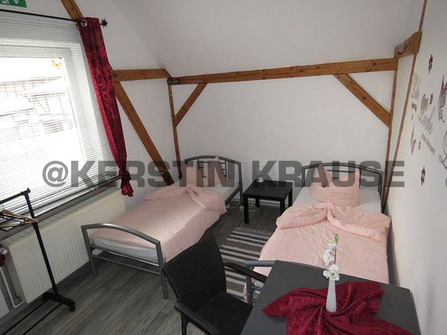 Kleines Schlafzimmer mit zwei Einzelbetten, einem Fenster und sichtbaren Holzbalken.