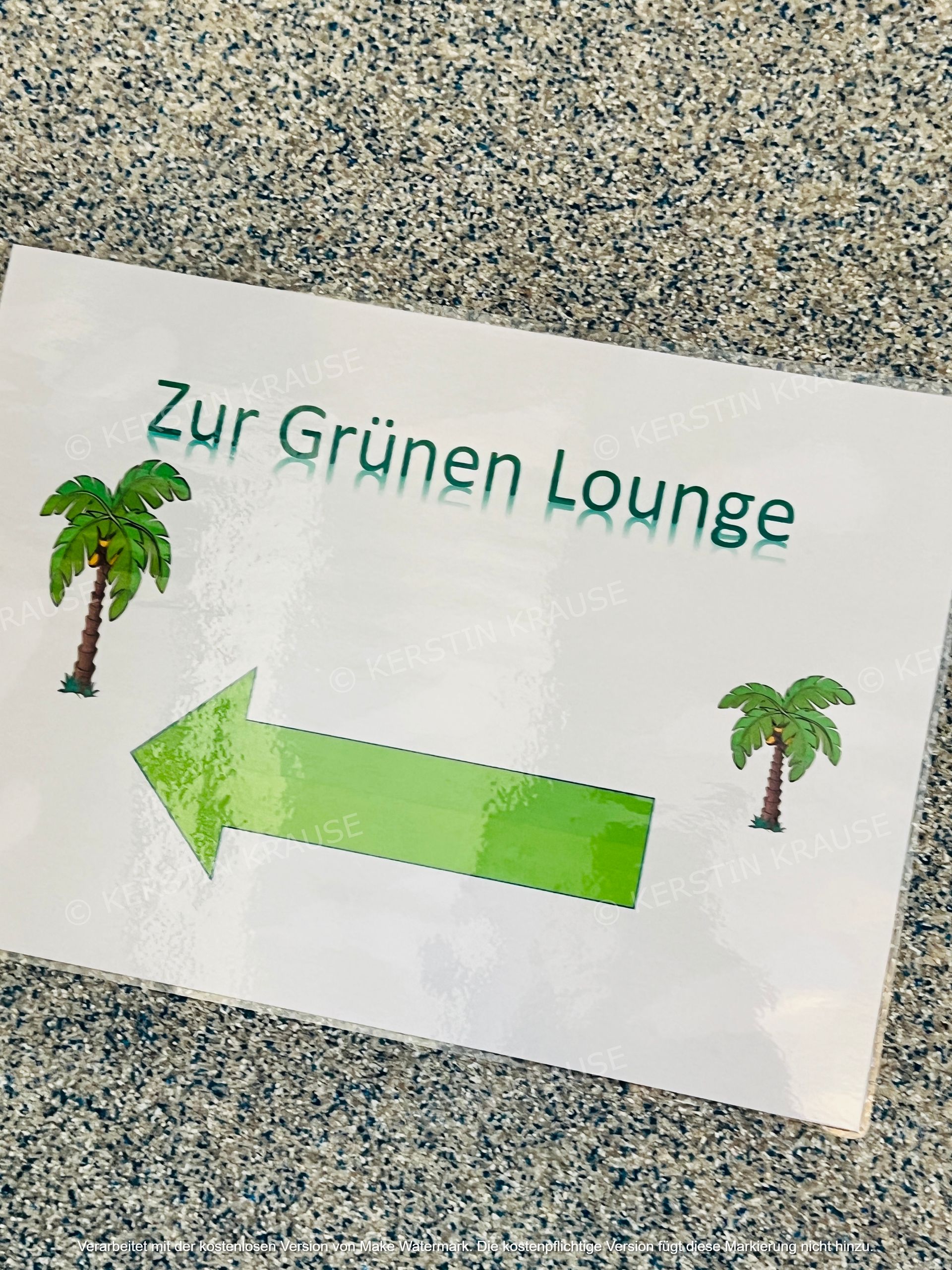 Weißes Schild mit der Aufschrift „Zur Grünen Lunge“ mit Palmen und einem grünen Pfeil nach links