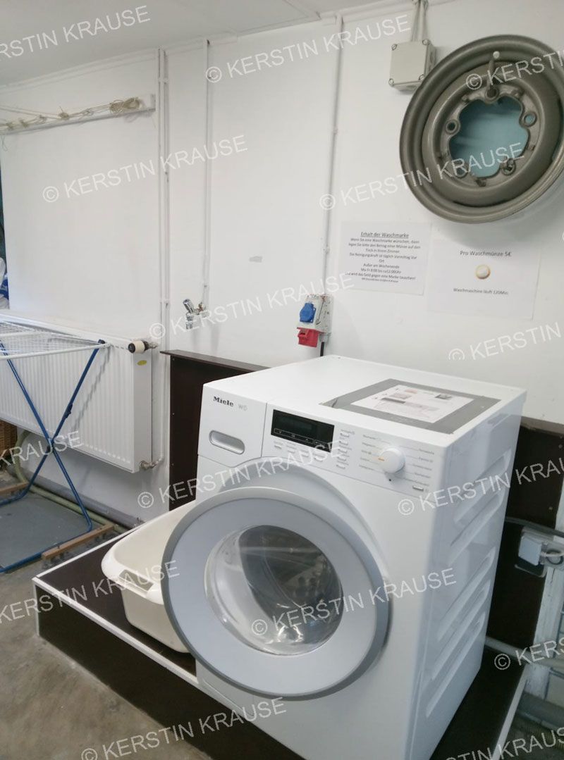 Eine Waschmaschine steht in einer Waschküche neben einem Waschbecken.