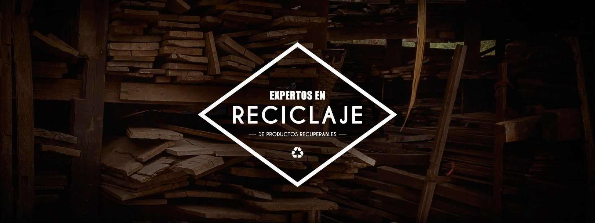 Logotipo de diamante blanco con el texto “RECICLAJE” sobre un fondo de tablones de madera en un entorno poco iluminado.