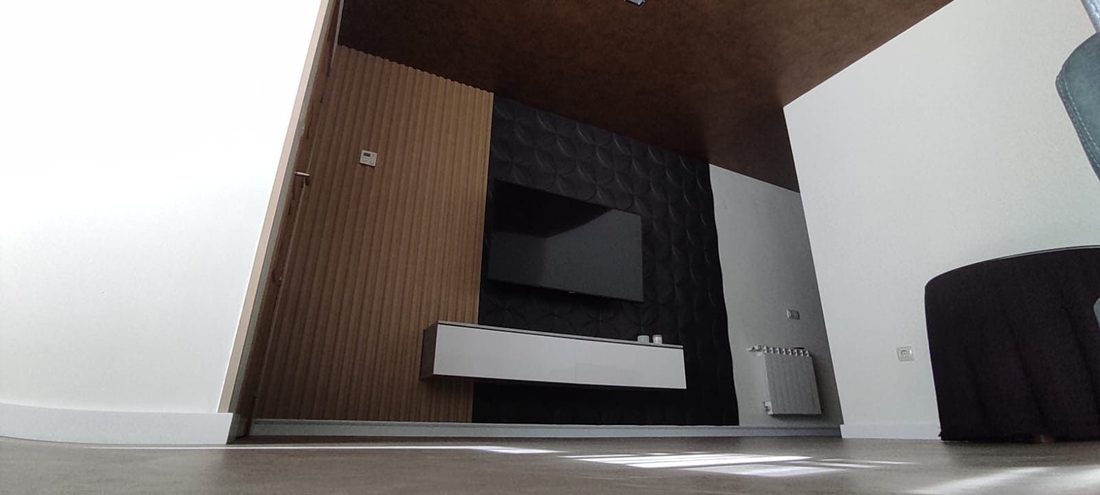 Sala de estar moderna con un televisor colgado en una pared oscura con textura.