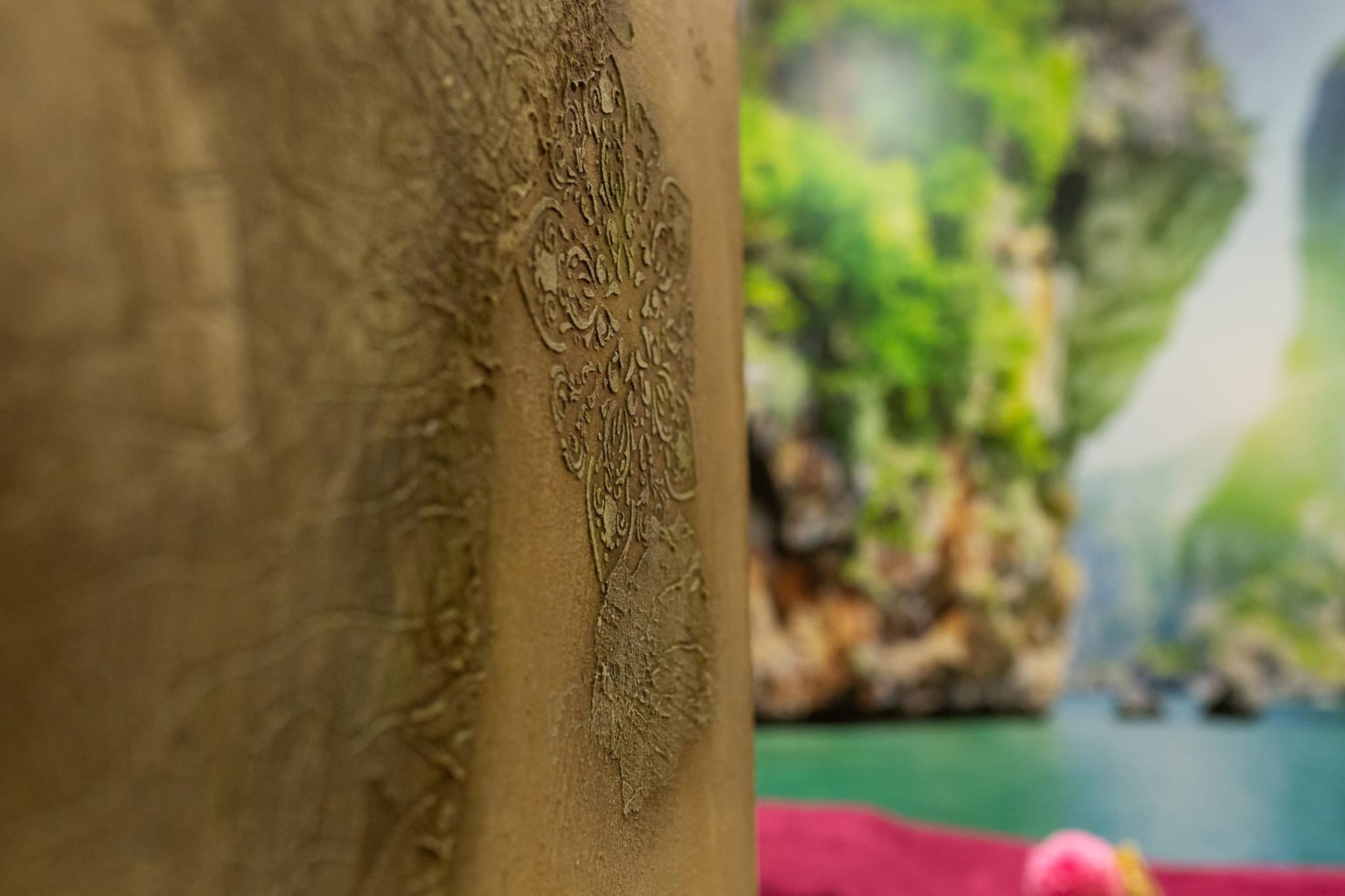 Primer plano de un tronco de árbol con textura, con una bahía tropical borrosa y acantilados al fondo.