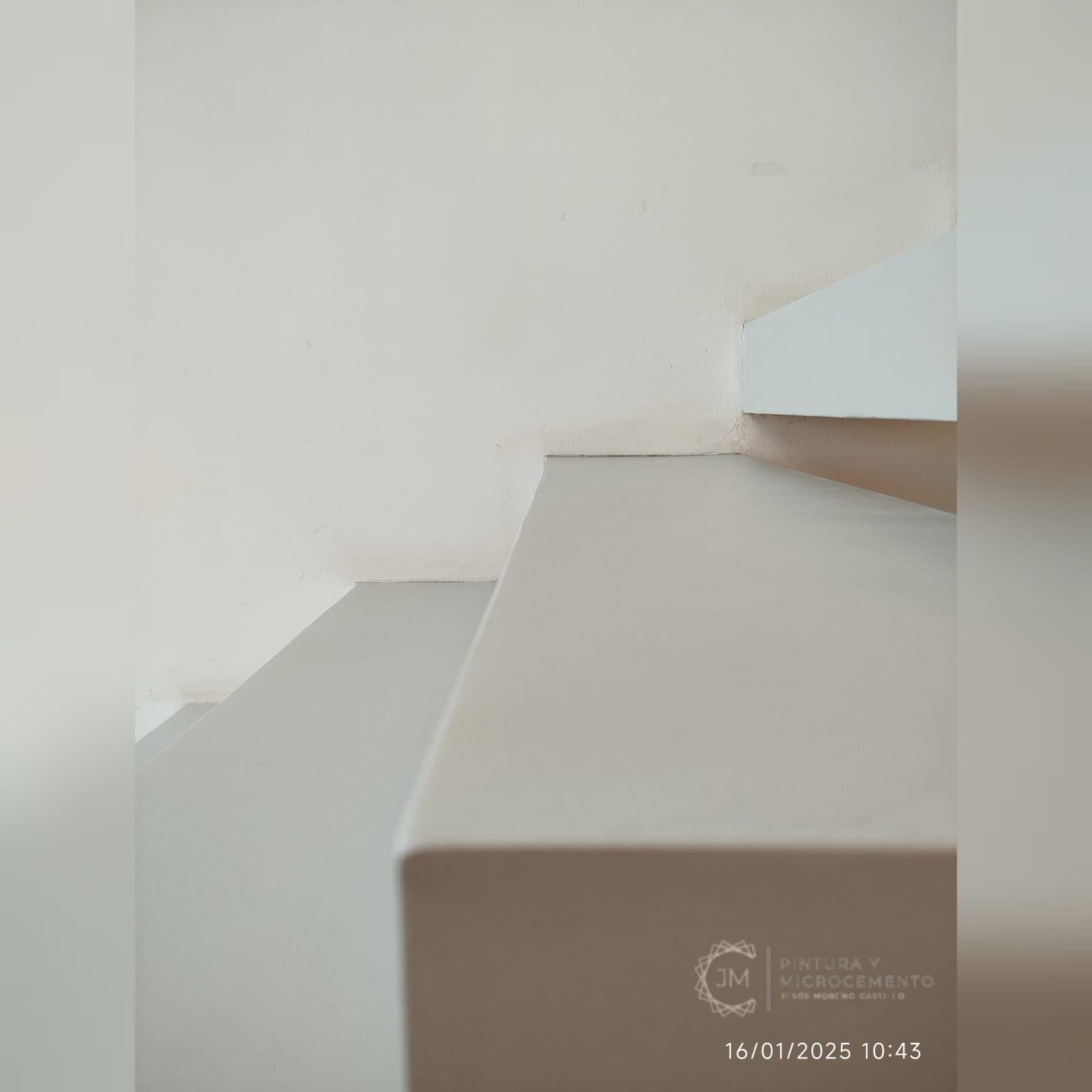 Escaleras blancas que conducen hacia arriba, contra una pared blanca sencilla.