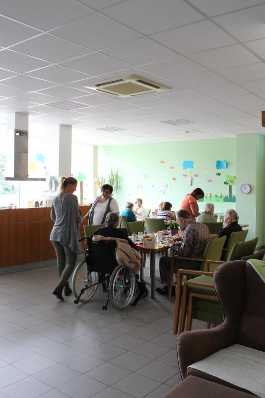 Eine Gruppe von Menschen sitzt an Tischen im Speisesaal eines Pflegeheims.