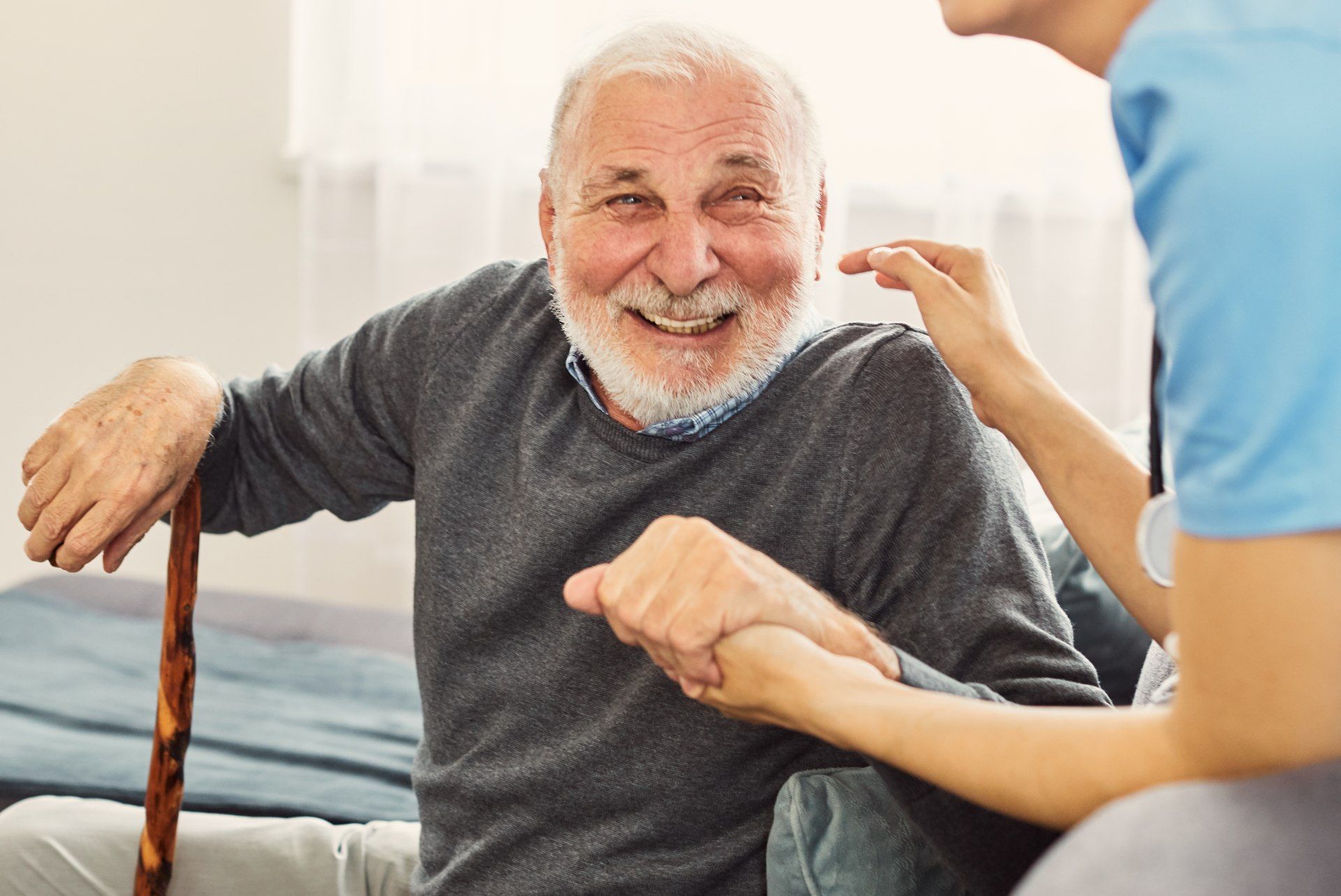Ein älterer Mann mit einem Gehstock wird von einer Krankenschwester versorgt.