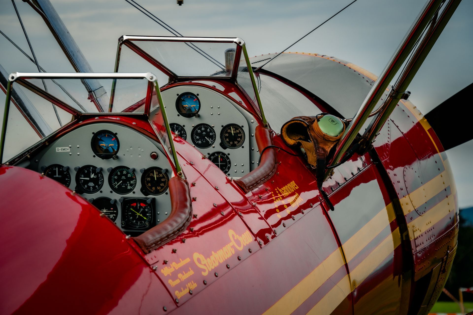 Rotes und goldenes Vintage-Doppeldecker-Cockpit mit Instrumententafel, Propeller und Kabinenhaube.