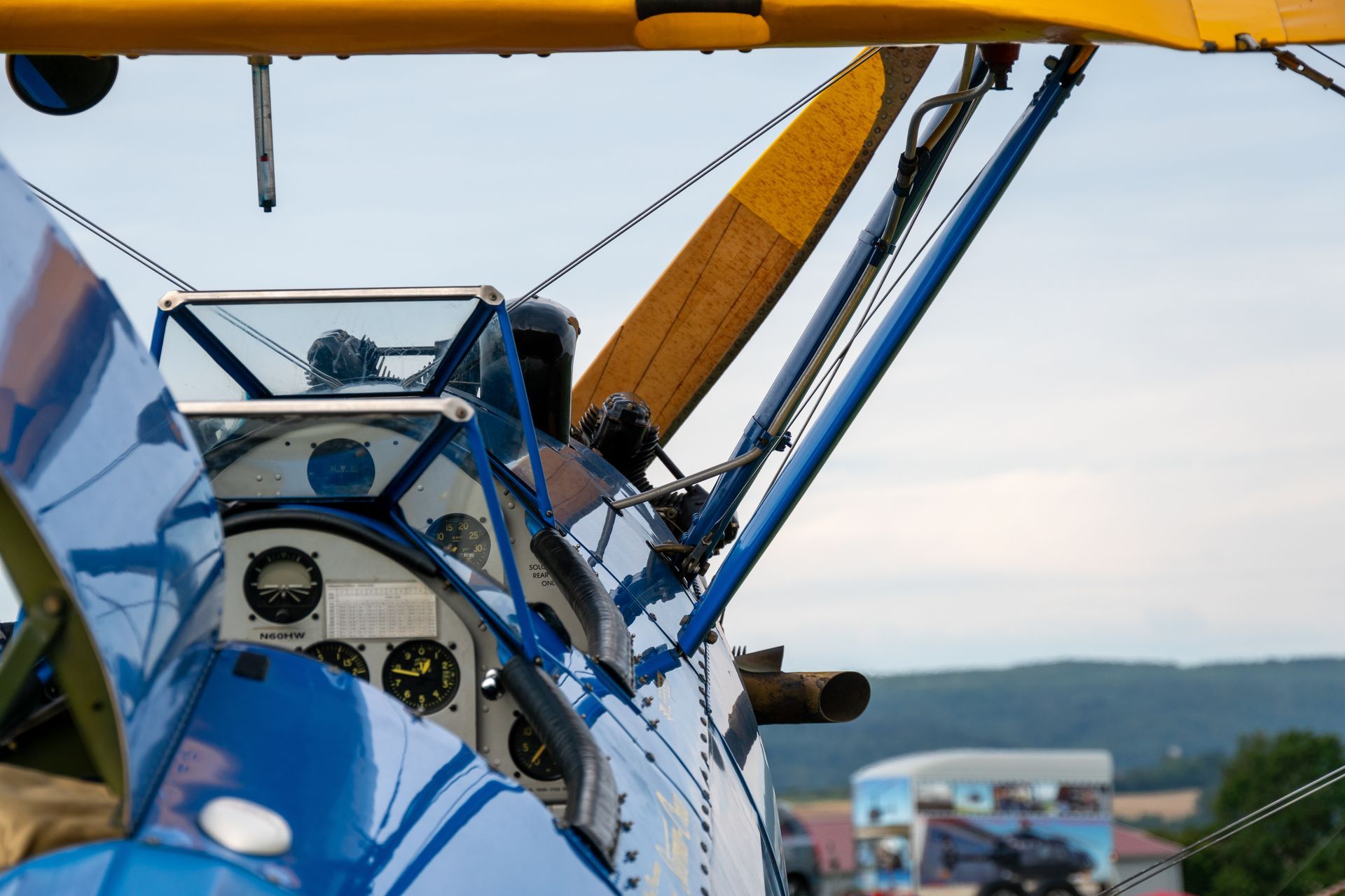 Blau-gelbes Doppeldecker-Cockpit mit Propeller und Instrumenten, aus nächster Nähe vor einer Landschaftskulisse betrachtet.