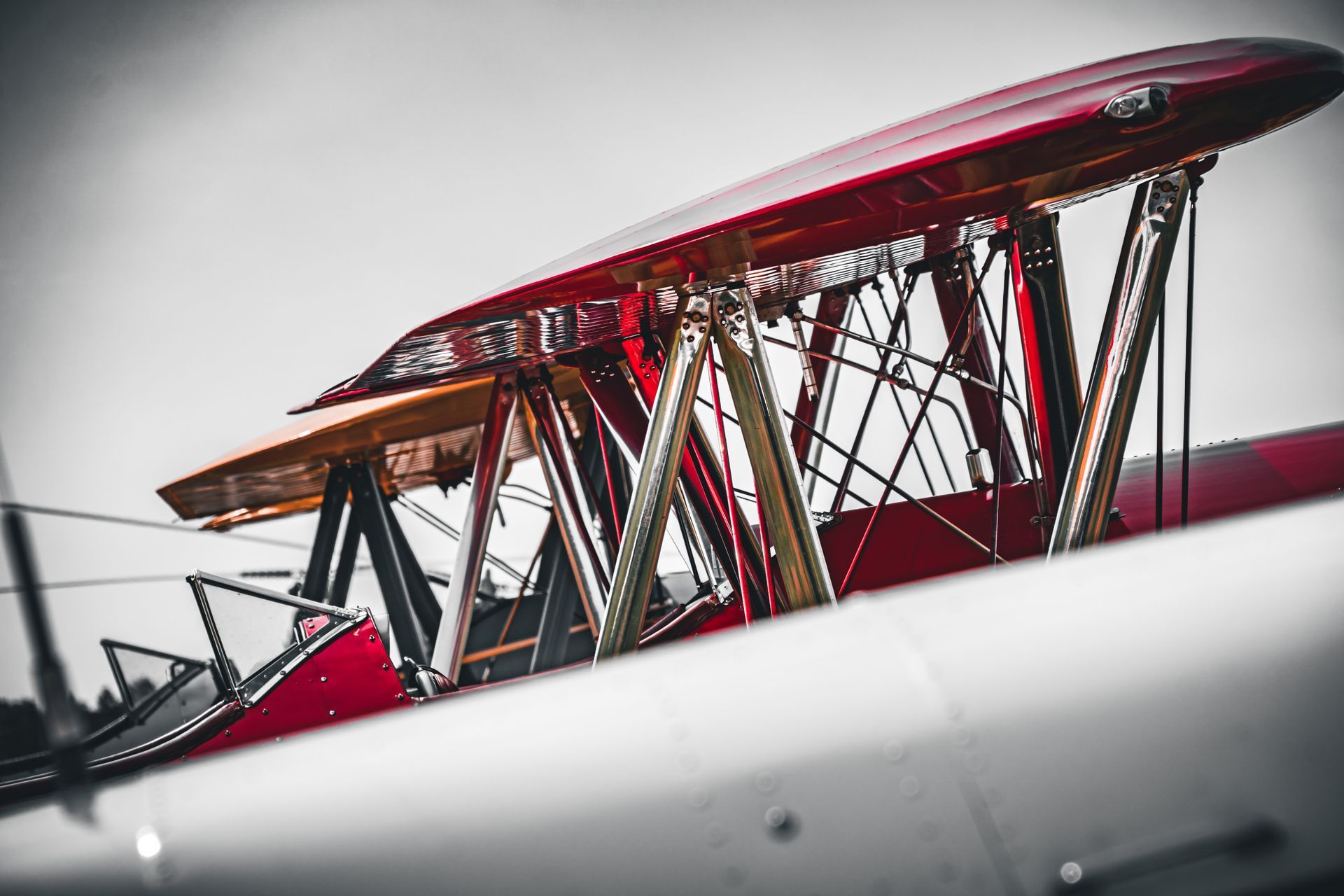 Roter Doppeldeckerflügel und Streben vor grauem Himmel, Nahaufnahme.