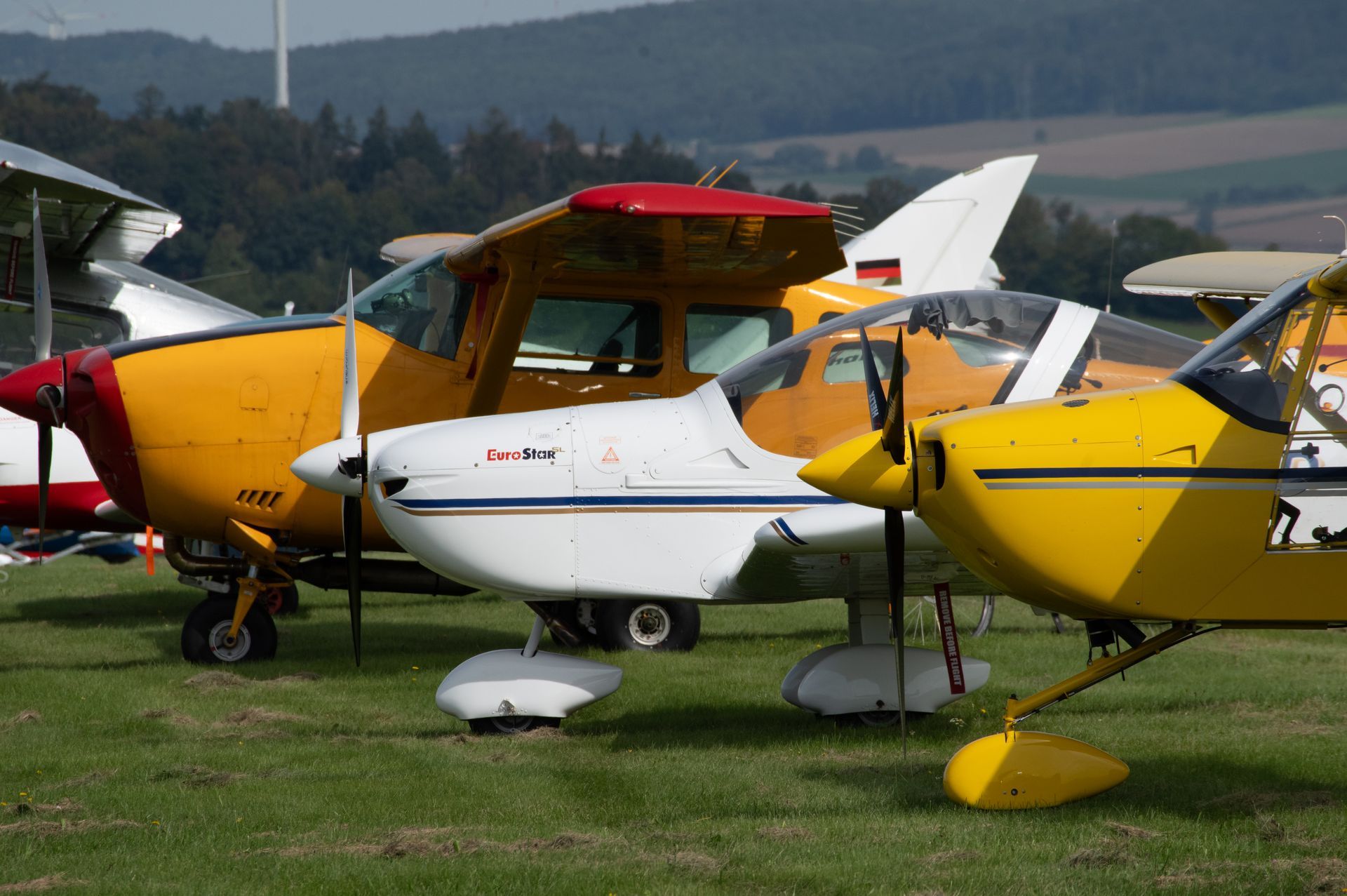 Mehrere kleine Flugzeuge parkten auf einer Wiese; gelbe und weiße Flugzeuge.