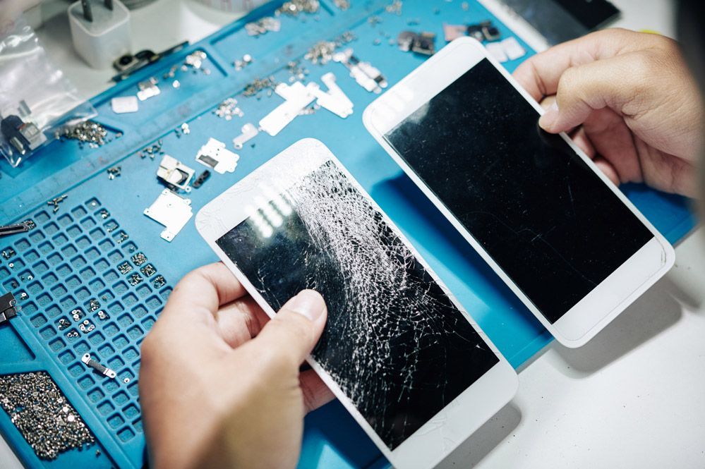 Una persona está arreglando un teléfono celular roto en una mesa.