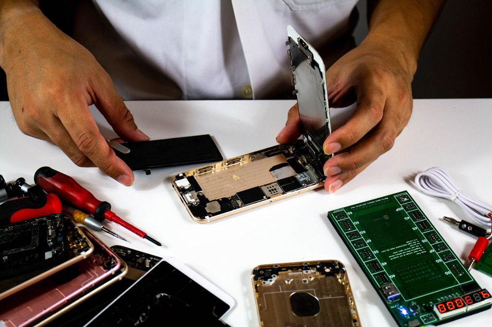 Una persona está desmontando un teléfono móvil sobre una mesa.