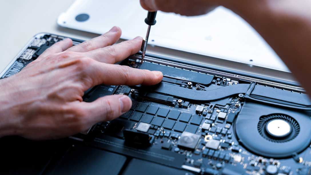 Una persona está arreglando una computadora portátil con un destornillador.