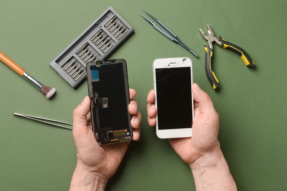 Una persona sostiene en sus manos un teléfono celular con la pantalla rota.