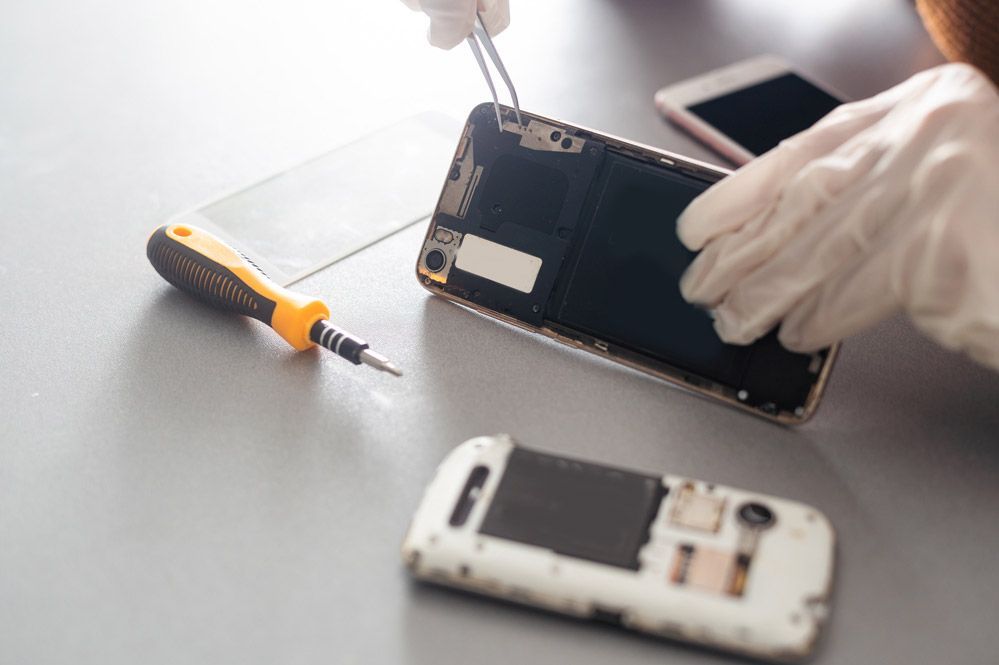 Una persona está reparando un teléfono celular en una mesa.