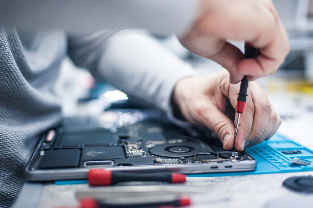 Una persona está arreglando una computadora portátil con un destornillador.