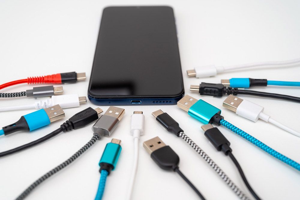 Un teléfono celular está rodeado de un montón de diferentes tipos de cables.