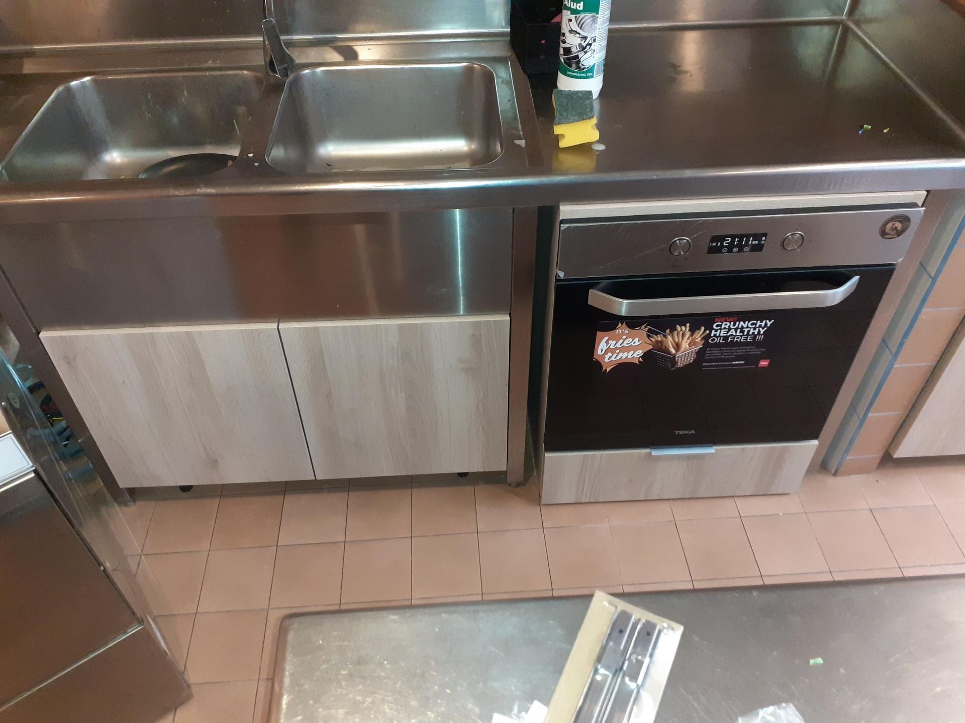 Fregadero y horno de cocina comercial de acero inoxidable. Revestimiento de madera clara.