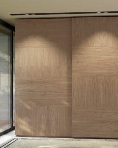 Puertas corredizas de armario de madera con patrón de vetas de madera horizontales, cerca de una ventana.