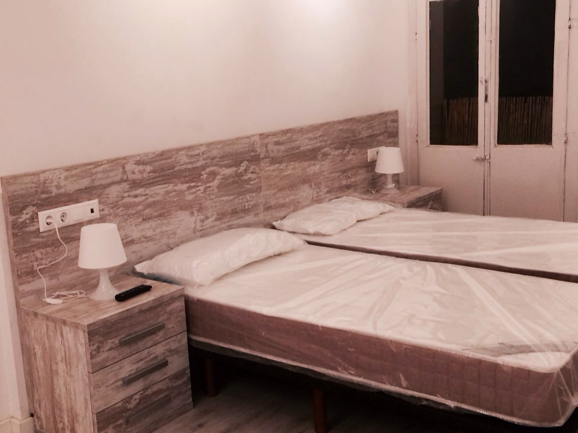 Dormitorio con dos camas individuales, mesitas de noche y cabecero de madera.