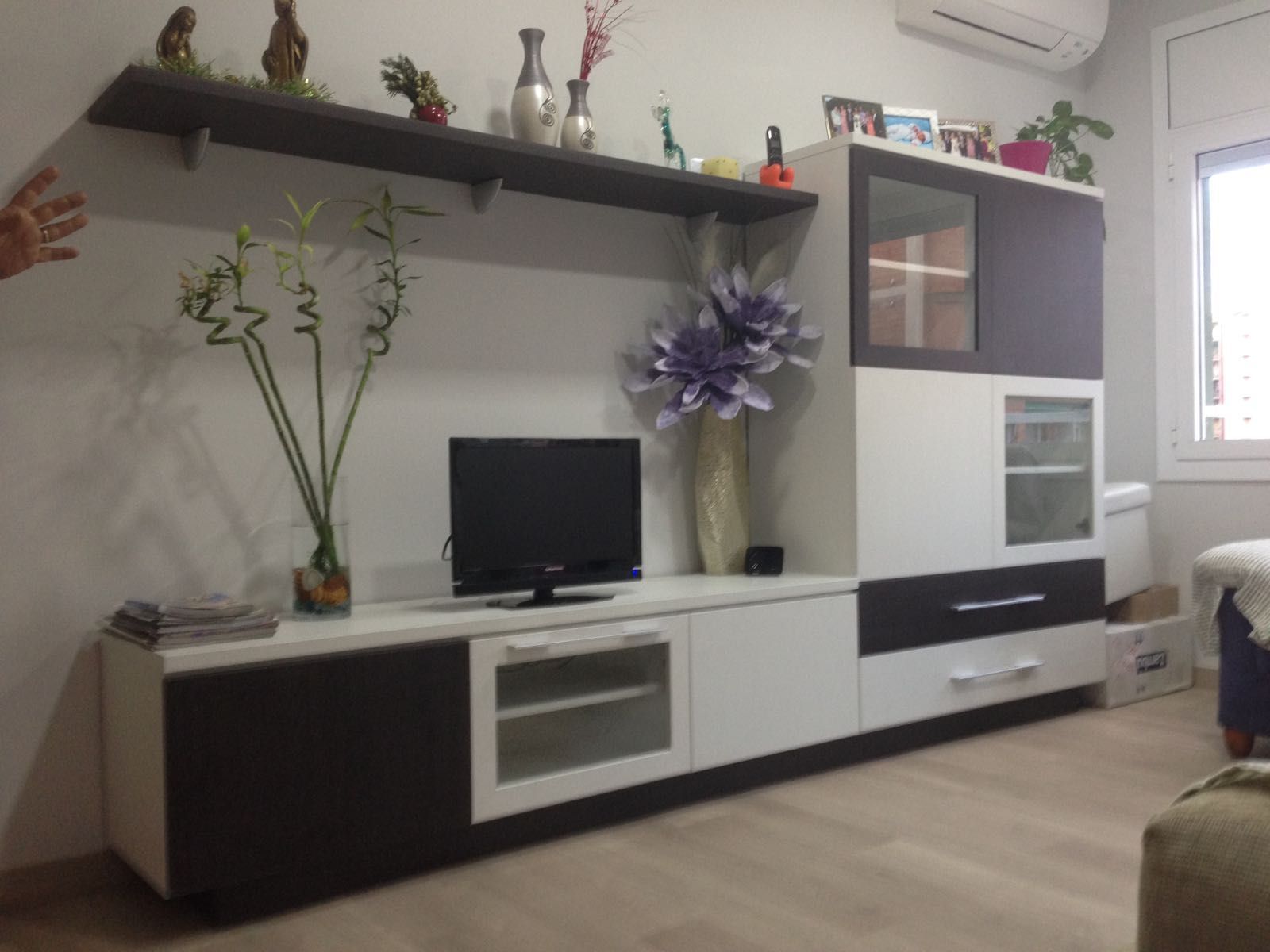 Centro de entretenimiento para sala de estar con TV, decoración y estantes; blanco y marrón.